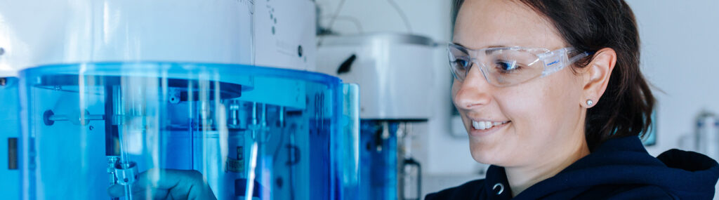 Eine Person mit dunklen Haaren und einer durchsichtigen Brille arbeitet an einer blauen, leicht durchsichtigen Plastikröhre.